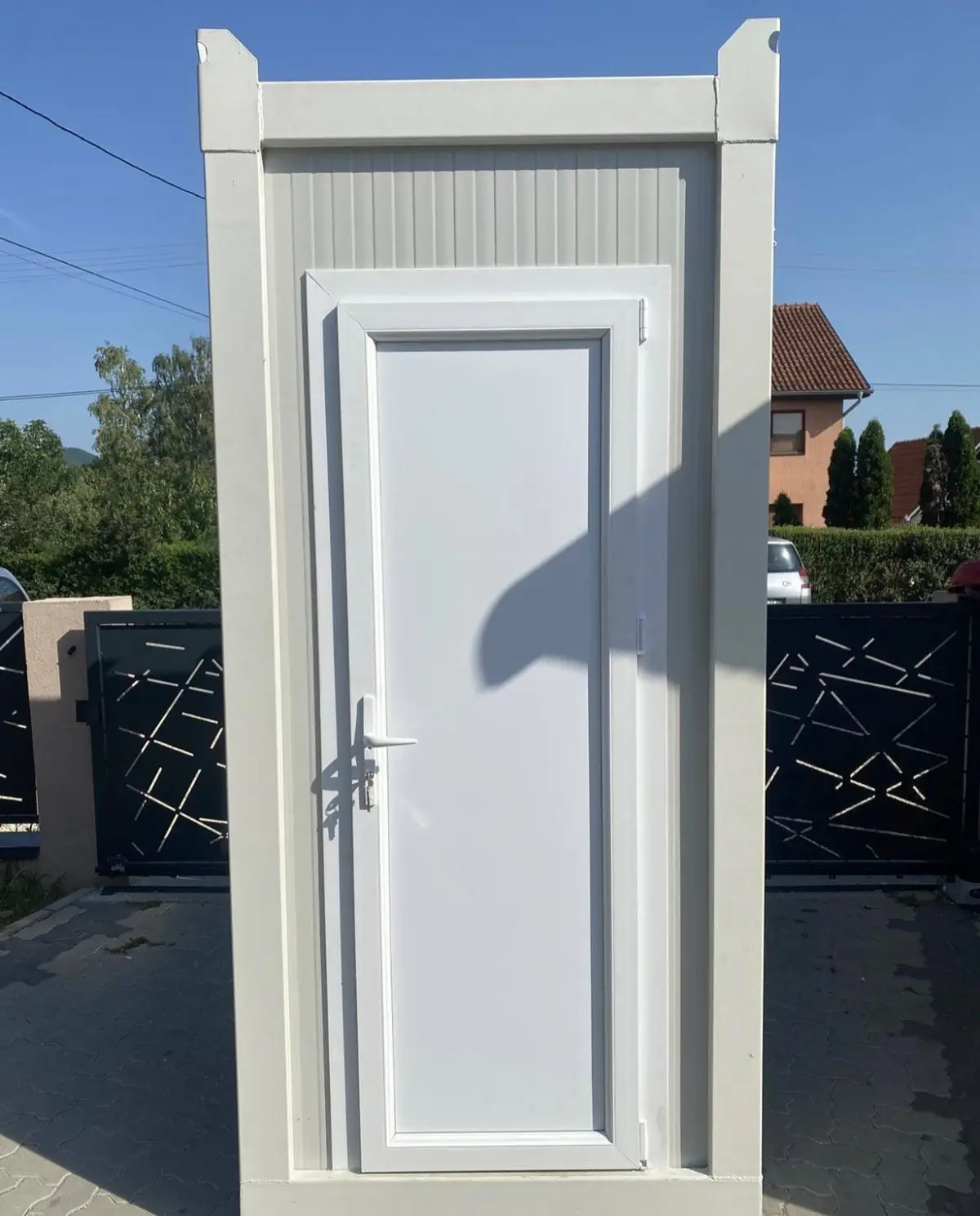 White flushing restroom cabin on a paver driveway