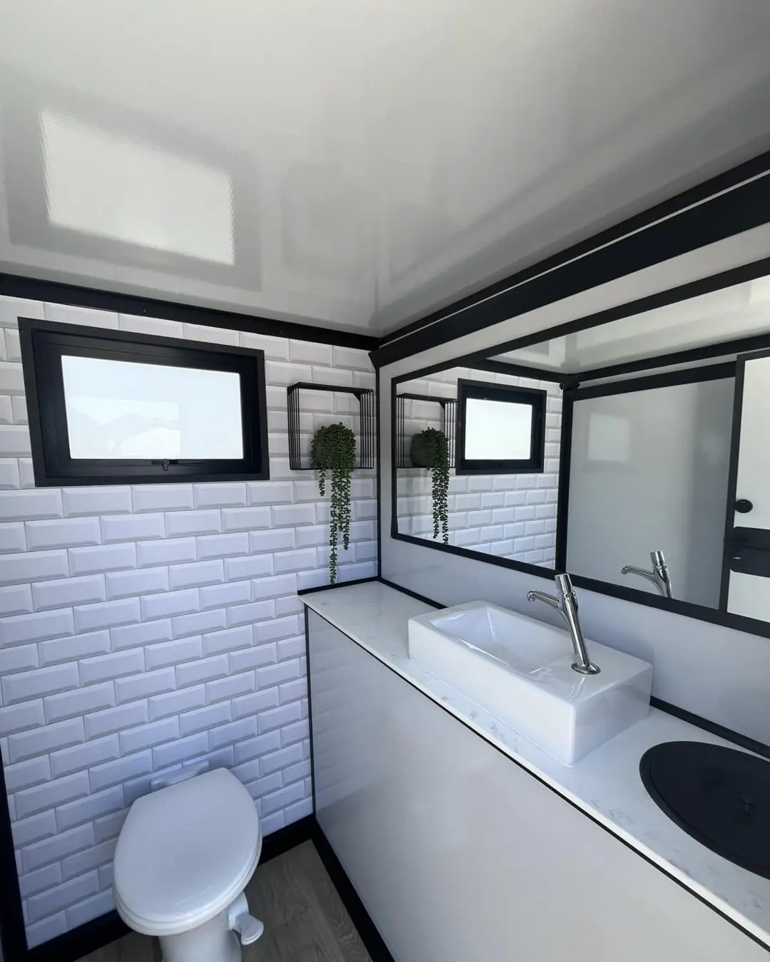 White tiled trailer stall with sink and plants